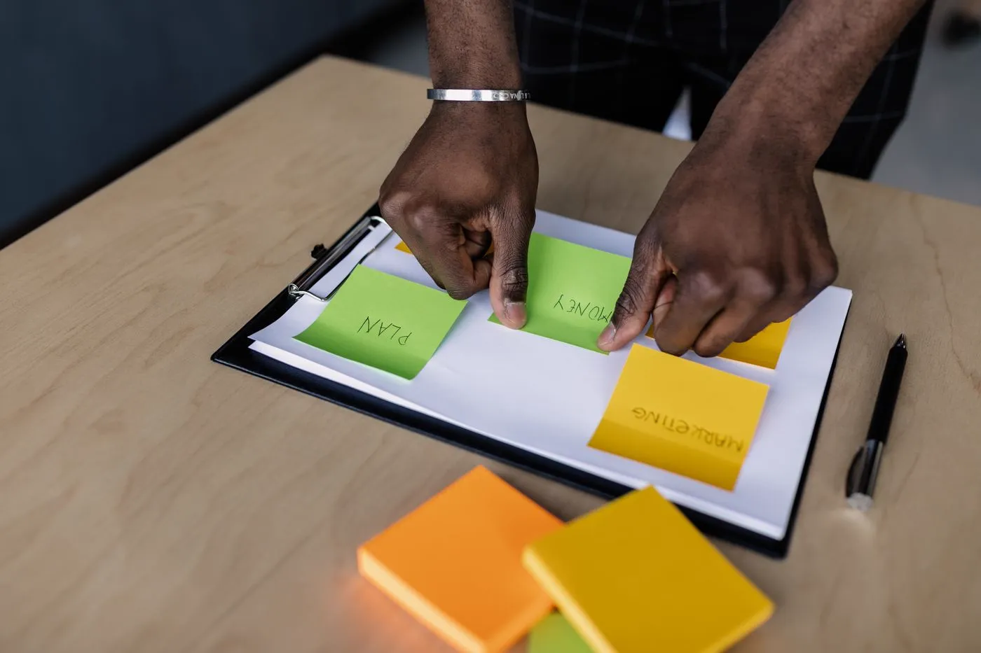 Hands sorting sticky notes on a clipboard